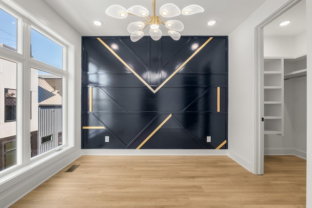 interior space featuring a notable chandelier, built in shelves, and wood-type flooring