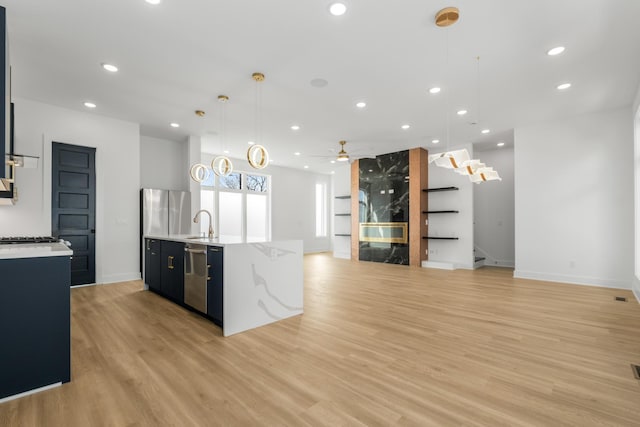 kitchen featuring sink, ceiling fan, appliances with stainless steel finishes, decorative light fixtures, and light wood-type flooring