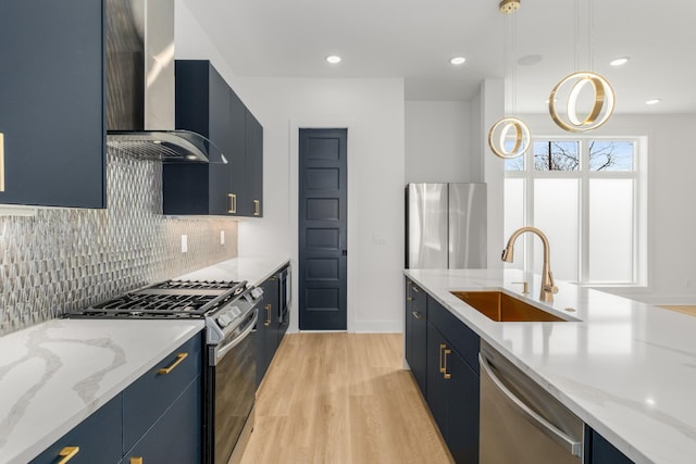 kitchen featuring decorative light fixtures, sink, stainless steel appliances, light stone countertops, and wall chimney exhaust hood