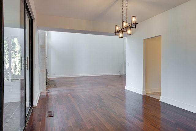 unfurnished room with dark hardwood / wood-style flooring and a notable chandelier