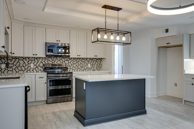 kitchen with tasteful backsplash, decorative light fixtures, a raised ceiling, a kitchen island, and stainless steel appliances