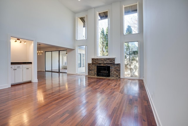 unfurnished living room featuring hardwood / wood-style flooring, a high ceiling, an inviting chandelier, and a fireplace