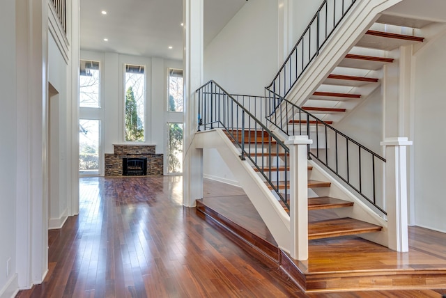 stairs featuring a high ceiling, wood-type flooring, and a fireplace