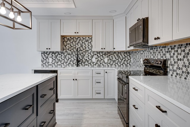 kitchen featuring decorative light fixtures, sink, white cabinets, and black appliances