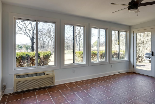 unfurnished sunroom with ceiling fan and a wall unit AC