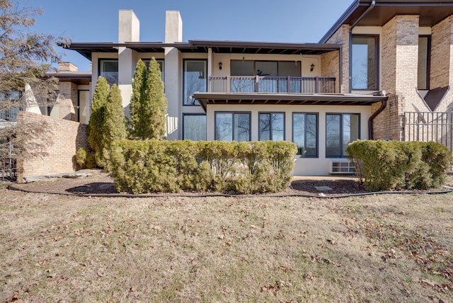 rear view of property featuring a balcony and a lawn