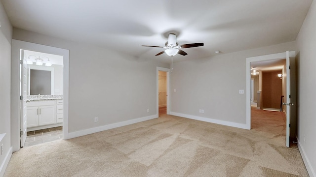 unfurnished bedroom featuring ensuite bathroom, sink, a spacious closet, and light colored carpet