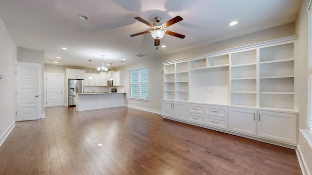 unfurnished living room featuring dark hardwood / wood-style floors and ceiling fan with notable chandelier