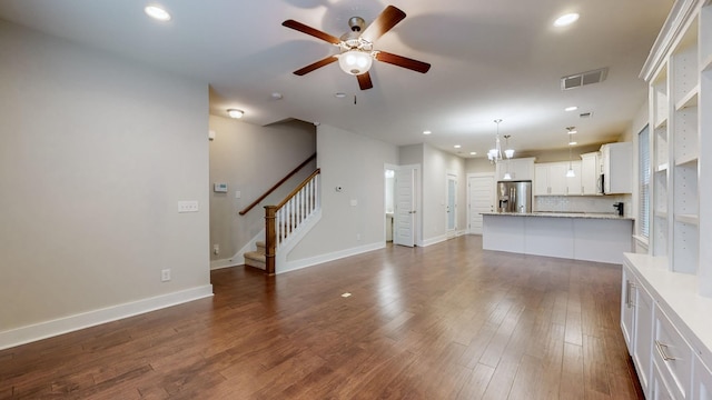 unfurnished living room featuring dark wood-type flooring and ceiling fan