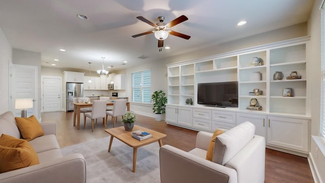 living room featuring ceiling fan with notable chandelier and light hardwood / wood-style floors