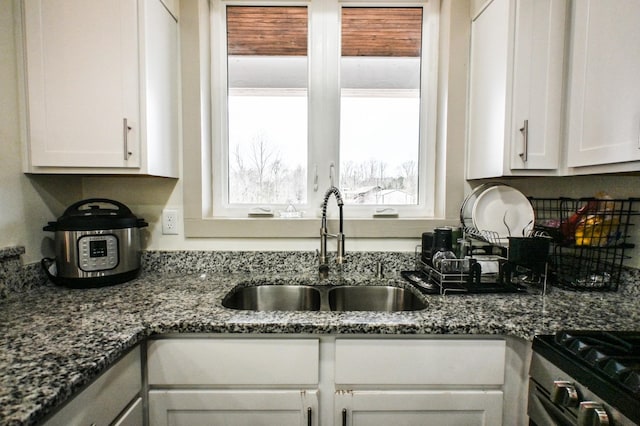 kitchen featuring white cabinetry, sink, stainless steel gas range, and stone counters