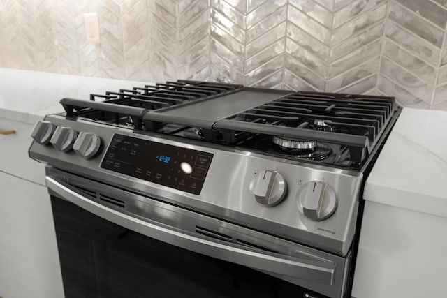 interior details with tasteful backsplash and stainless steel range with gas cooktop