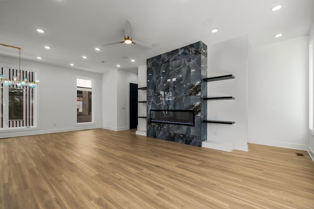 unfurnished living room with ceiling fan, a high end fireplace, and light wood-type flooring