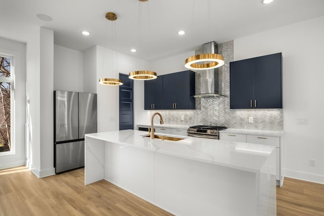 kitchen featuring wall chimney exhaust hood, sink, hanging light fixtures, a center island with sink, and stainless steel appliances