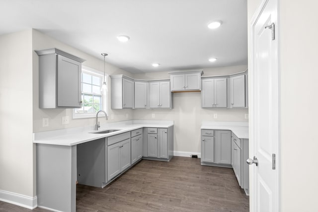 kitchen featuring gray cabinets, sink, dark wood-type flooring, and decorative light fixtures