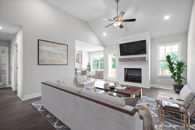 living room with ceiling fan, a large fireplace, dark hardwood / wood-style flooring, and high vaulted ceiling