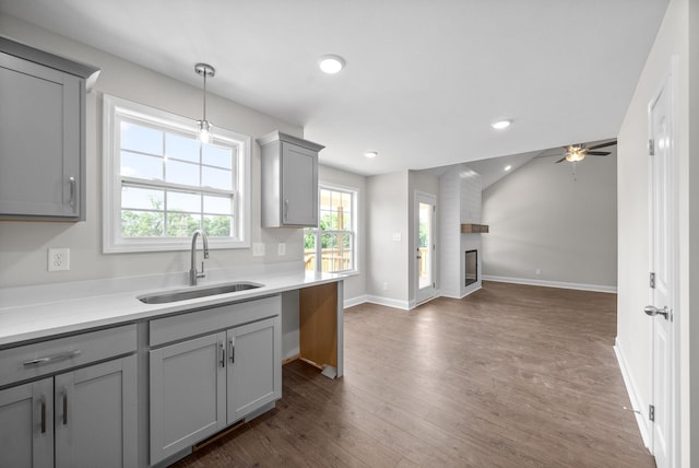 kitchen featuring pendant lighting, sink, gray cabinets, dark hardwood / wood-style floors, and a large fireplace