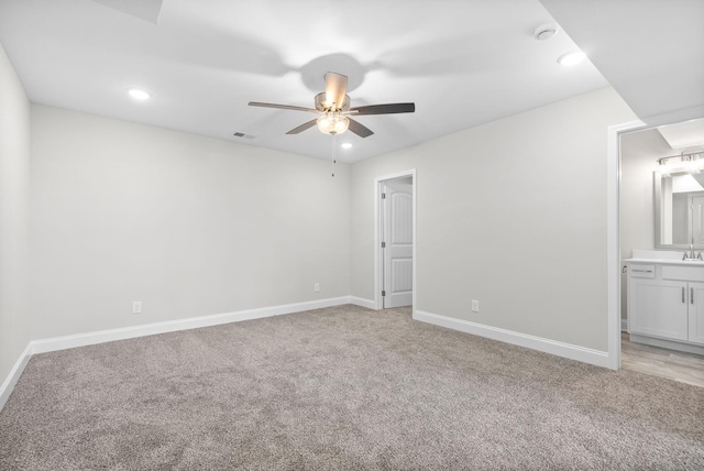 unfurnished bedroom featuring ceiling fan, light colored carpet, ensuite bathroom, and sink