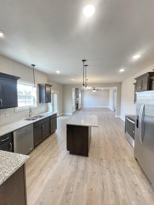 kitchen featuring pendant lighting, sink, stainless steel appliances, and a center island