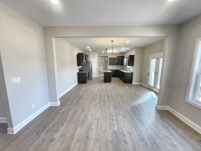 unfurnished living room featuring hardwood / wood-style flooring, sink, and an inviting chandelier