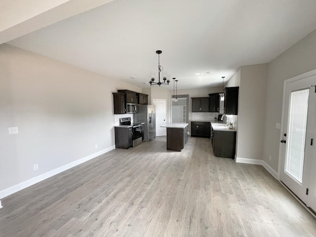 kitchen with sink, decorative light fixtures, a center island, appliances with stainless steel finishes, and hardwood / wood-style floors