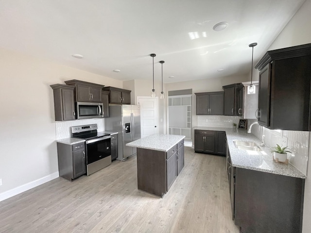 kitchen featuring pendant lighting, sink, appliances with stainless steel finishes, light hardwood / wood-style floors, and a kitchen island