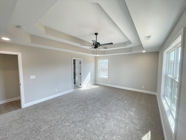 spare room featuring carpet floors, a raised ceiling, and ceiling fan