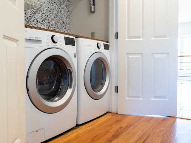 washroom featuring washing machine and dryer, laundry area, and light wood finished floors