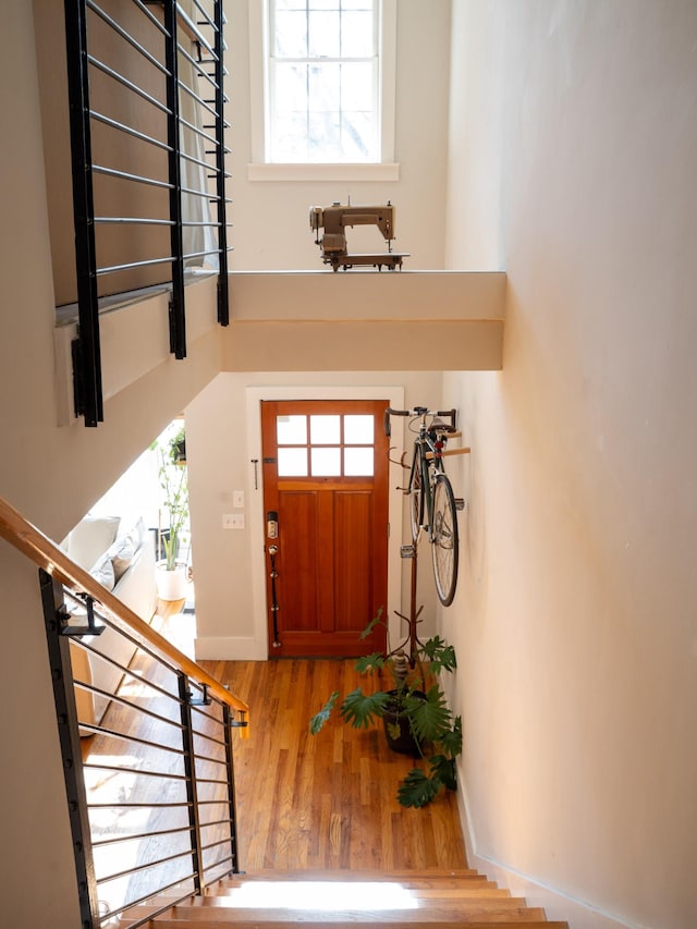 entryway with stairway, wood finished floors, baseboards, and a towering ceiling