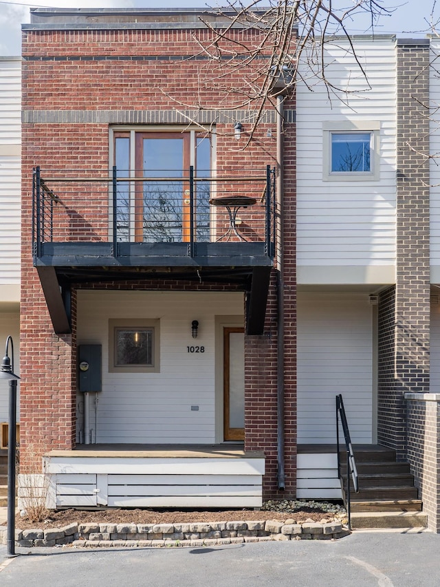 view of front of home with a balcony and brick siding