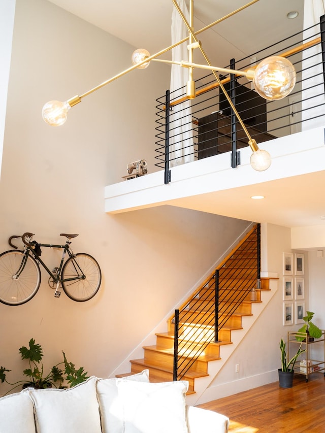 stairs with a high ceiling, baseboards, and wood finished floors