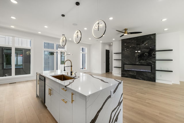 kitchen featuring sink, white cabinetry, hanging light fixtures, a center island with sink, and stainless steel dishwasher