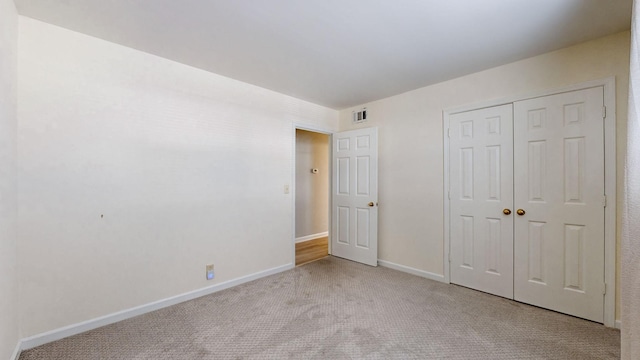 unfurnished bedroom with a closet and light carpet