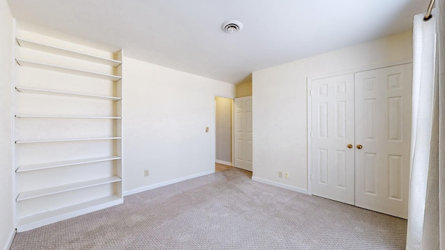 unfurnished bedroom featuring light carpet and a closet