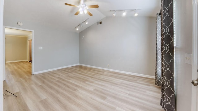 spare room with vaulted ceiling, track lighting, ceiling fan, and light wood-type flooring