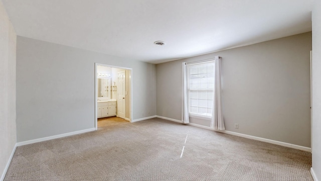 unfurnished bedroom featuring light carpet and ensuite bath