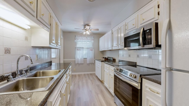 kitchen featuring sink, white cabinetry, appliances with stainless steel finishes, ceiling fan, and light hardwood / wood-style floors