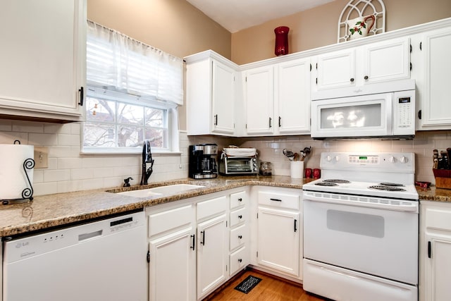 kitchen featuring light stone countertops, sink, white cabinets, and white appliances