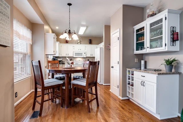 dining space featuring a notable chandelier and light wood-type flooring