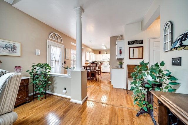 office area with decorative columns and light hardwood / wood-style floors