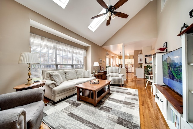 living room with wood-type flooring, vaulted ceiling with skylight, and ceiling fan