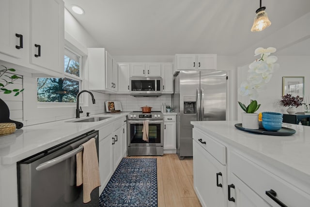 kitchen with sink, white cabinetry, tasteful backsplash, appliances with stainless steel finishes, and pendant lighting