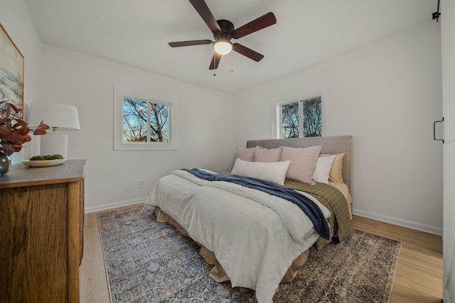 bedroom with ceiling fan, hardwood / wood-style floors, and multiple windows