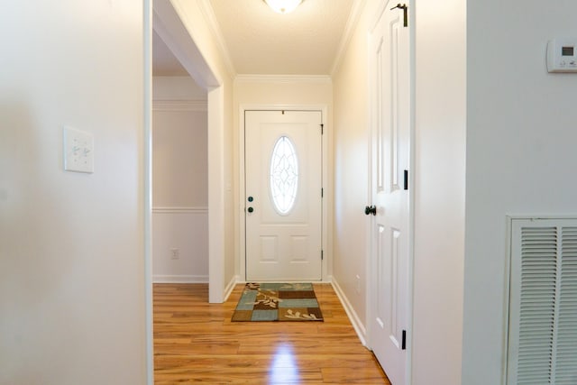 entryway with crown molding, a textured ceiling, and light hardwood / wood-style floors