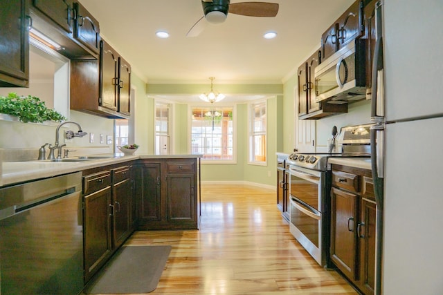 kitchen featuring pendant lighting, ornamental molding, stainless steel appliances, and light hardwood / wood-style floors