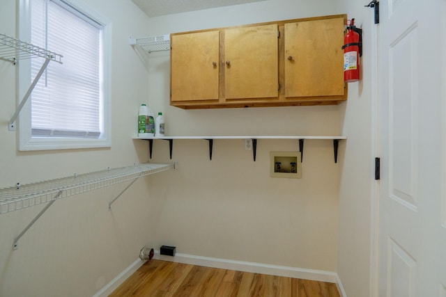 laundry area featuring cabinets, washer hookup, and light hardwood / wood-style flooring