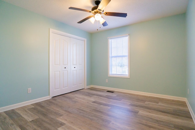 unfurnished bedroom featuring hardwood / wood-style flooring, ceiling fan, and a closet