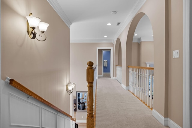 hallway with ornamental molding and light colored carpet