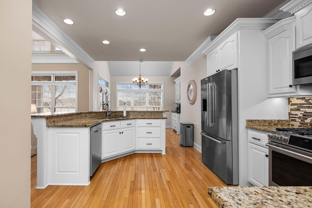 kitchen featuring white cabinetry, decorative light fixtures, stainless steel appliances, and dark stone countertops