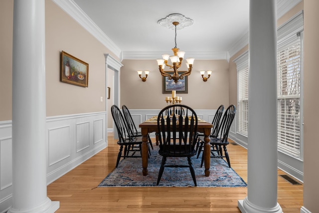 dining area with an inviting chandelier, light hardwood / wood-style flooring, and ornate columns